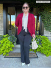 Miik model Bri (5'5", xlarge) smiling wearing a black pant, a bordeaux soft blazer with Miik's Rhoda tie neck blouse in natural with accessories in the same colour 