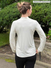Miik model Johanna (five feet six, size xsmall) standing with her back towards the camera showing the back of Miik's Rhoda tie neck blouse in natural