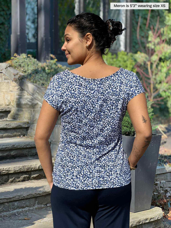 Miik model Meron (5’3”, xsmall) standing with her back towards the camera showing the back of Miik's Rio reversible dolman tee in baby's breath print 