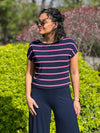 Miik model Meron (5'3" xsmall) looking away wearing Miik's Rio reversible dolman tee in beach house stripe with a navy wide leg pant and sunglasses 