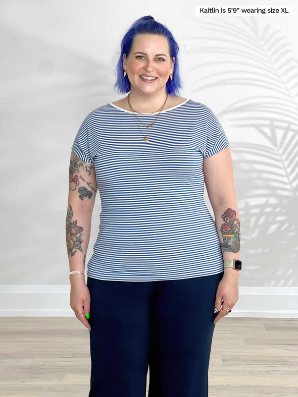Miik model Kaitlin (5'9", xlarge) smiling wearing Miik's Rio reversible dolman tee in cobalt mini stripe with a navy pant 