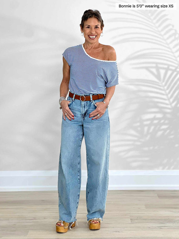 Miik model Bonnie (5'0", xsmall, petite) smiling wearing Miik's Rio reversible dolman tee in cobalt mini stripe along with a straight leg jeans  