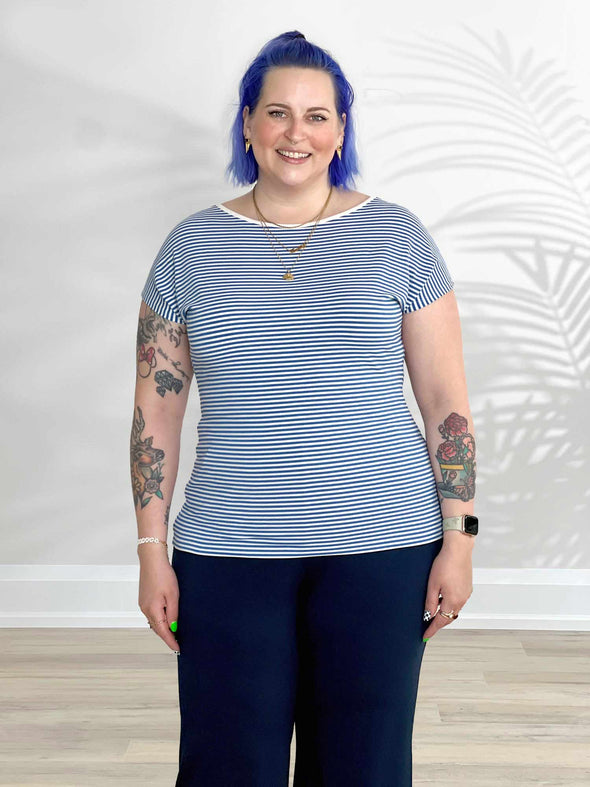 Miik model Kaitlin (5'9", xlarge) smiling wearing Miik's Rio reversible dolman tee in cobalt mini stripe with a navy pant