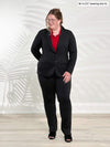 Miik model Bri (5'5", xlarge) wearing Miik's Roma pull-on straight leg ankle pant in black with a blazer in the same colour and a collared shirt in poppy red 