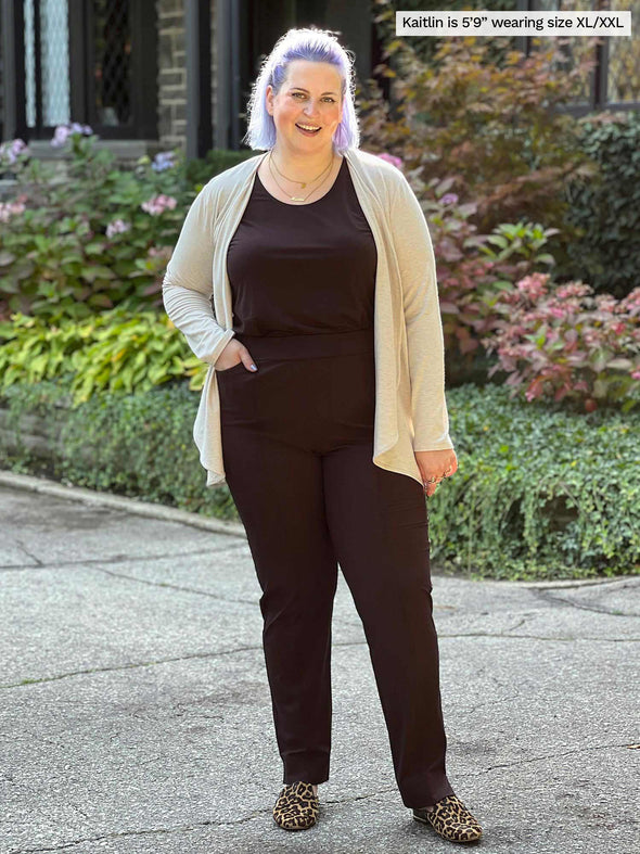 Miik model Kaitlin (size XXL, 5 foot 9) wearing the Rory waterfall cardigan in beige camel melange layered over a dark brown tank and pants.