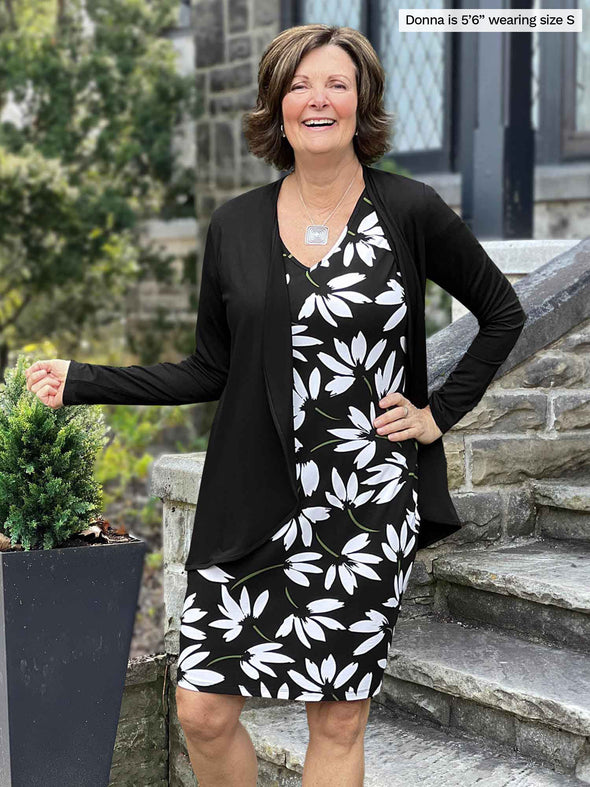 Miik founder Donna (5'6", small) smiling wearing a printed dress along with Miik's Rory waterfall cardigan in black
