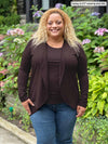 Miik model Carley (five feet two, xxlarge) smiling wearing Miik's Rory waterfall cardigan in dark chocolate along with a matching colour tank top and jeans 