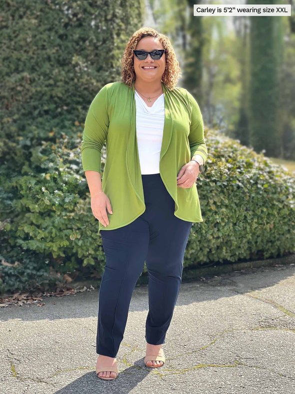 Miik model Carley (5'2, xxlarge) smiling wearing Miik's Rory waterfall cardigan in green moss with a white top and navy dress pant