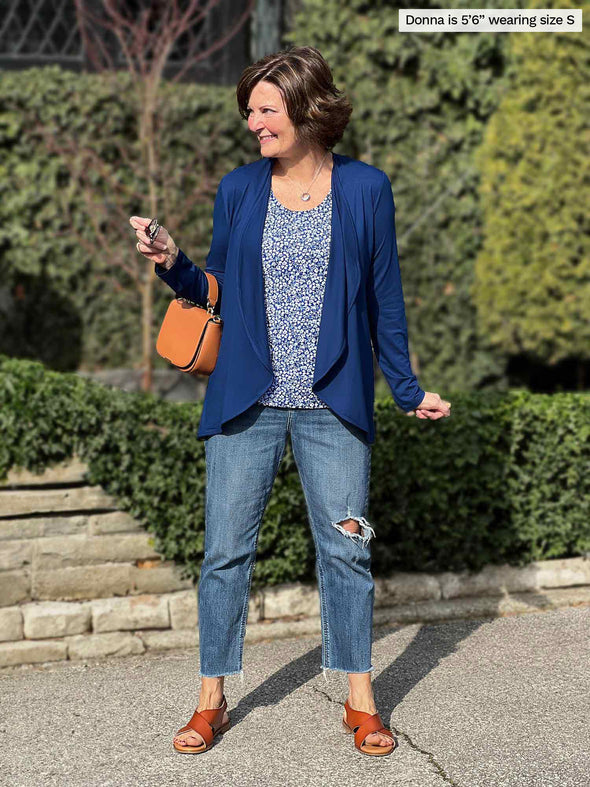 Miik founder Donna (5'6", small) smiling and looking away wearing a ripped jeans, a tank top in the baby's breath print and Miik's Rory waterfall cardigan in ink blue