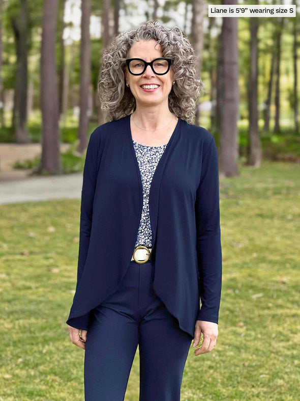 Miik model Liane (5'9", small) smiling wearing Miik's Miik's Rory waterfall cardigan in navy with a pant in the same colour 