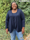 Miik model plus size Kimesha (5'8", size 3x) smiling wearing a ripped jeans along with Miik's Rory waterfall cardigan in navy with a matching colour tank top