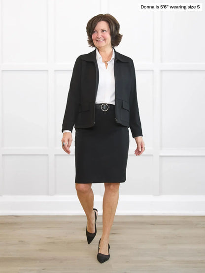 Woman wearing a black suit with a white shirt against a white background 
