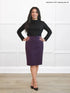 Woman wearing a black top and purple skirt against a white background 