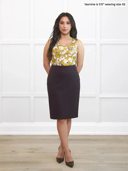 Woman wearing a floral top and dark brown skirt against a white background 