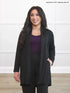Woman wearing a black cardigan over a purple top and black pants on a white background 