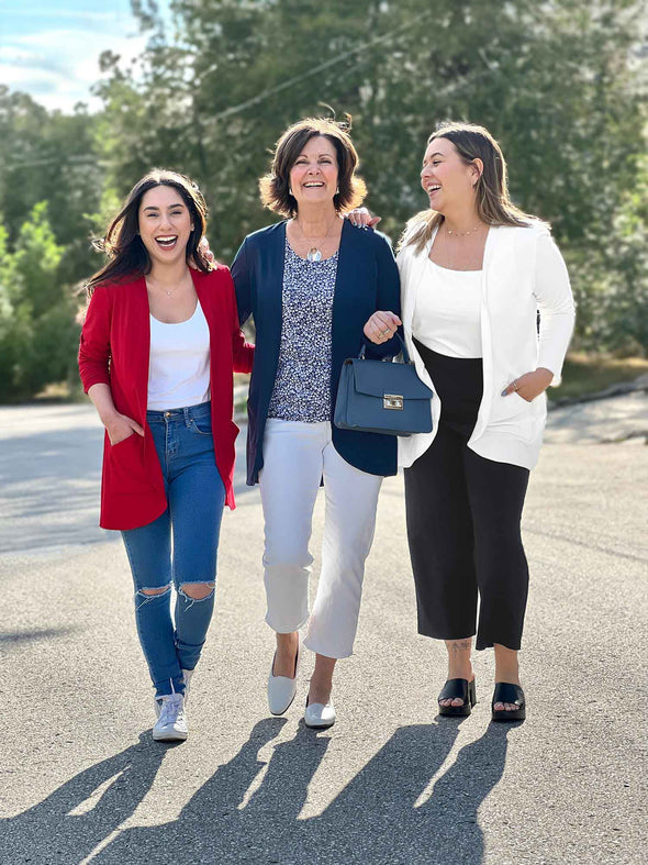Miik models Yasmine and Christal, and Miik founder Donna laughing all wearing Miik's Sade open-front pocket cardigan. Yasmine is wearing in poppy red colour, Donna in navy and Christal in natural. They are all showing different ways to style the new Miik cardigan 