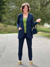 Miik founder Donna (5'6", small) smiling wearing a navy pant along with a green moss tank and Miik's Sade open-front pocket cardigan in navy