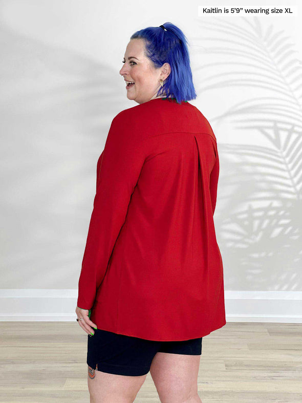 Miik model Kaitlin (5'9", xlarge) standing with her back to the camera showing the details of Miik's Sade open-front pocket cardigan in poppy red