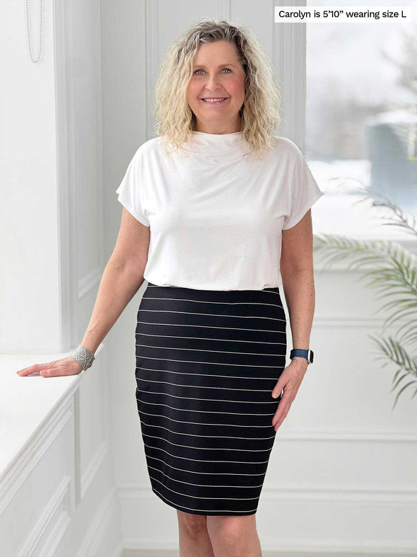 Miik model Carolyn (5'10", large) smiling wearing a white tee tucked in Miik's Salma striped pencil skirt in black wide pinstripe 