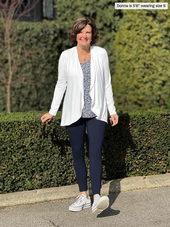 Miik founder Donna (5'6", small) smiling wearing Miik's Seana high waisted pocket legging in navy with a waterfall cardigan in white and a printed tank 