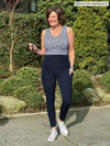 Miik founder Donna (5'6", small) smiling and looking away wearing Miik's Seana high waisted pocket legging in navy with a tank top in baby's breath 