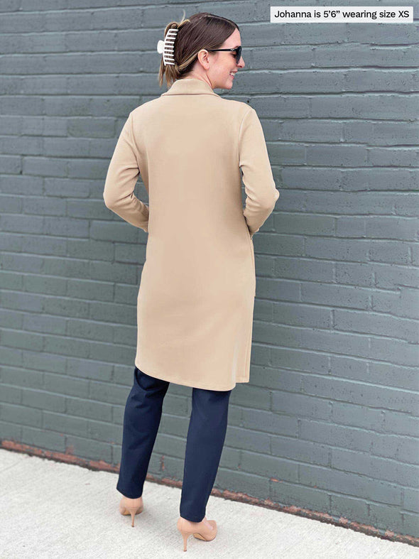 Miik model Johanna (five feet six, size extra small) standing with her back towards the camera showing the back of Miik's Serena long coat with pockets