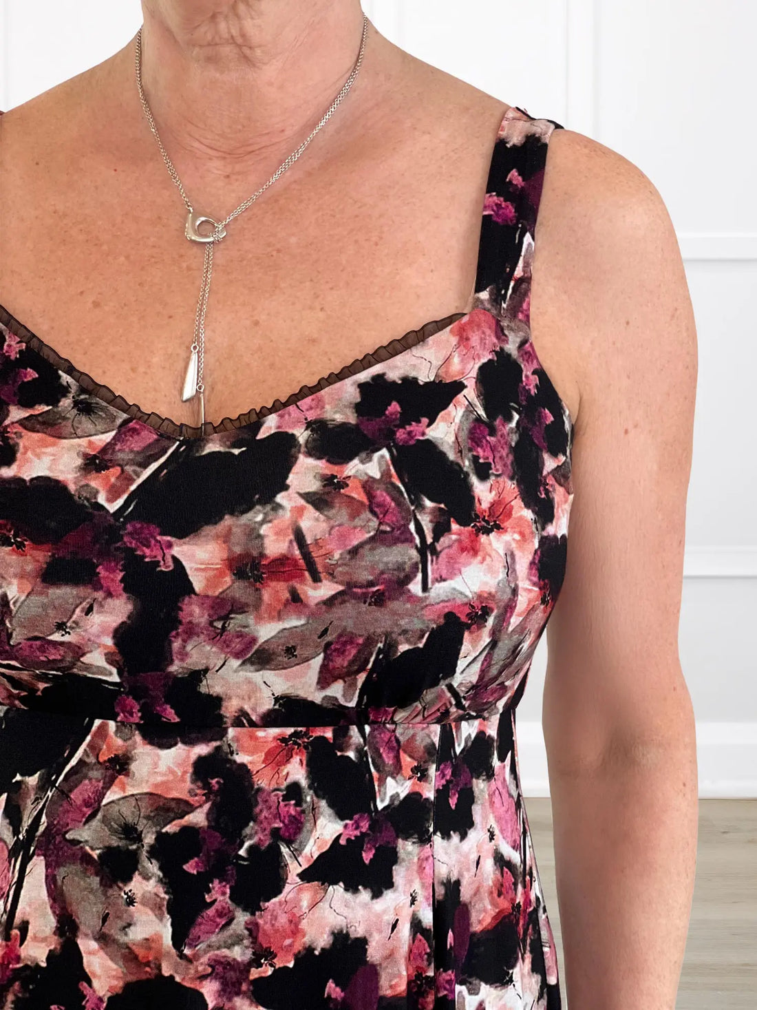 A close-up of the Seville midi dress, showing the neckline with the ruffled trim, empire waist, and straps. 
