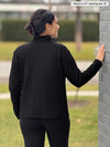 Miik model Meron (5’3”, xsmall) standing with her back towards the camera showing the back of Miik's Shaelyn full zip luxe fleece jacket