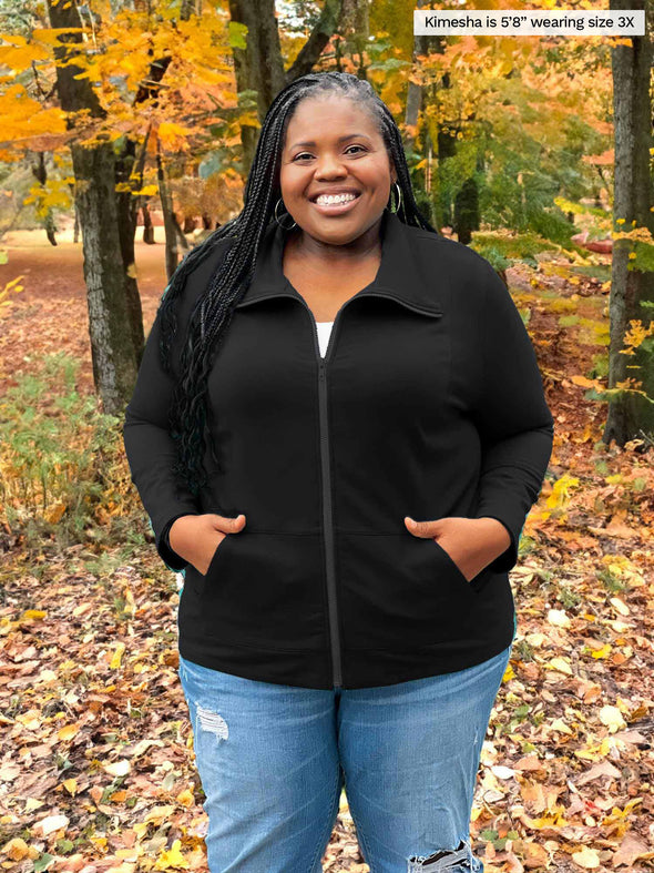Miik model plus size Kimesha (5'8", size 3x) smiling wearing Miik's Shaelyn full zip luxe fleece jacket in black with jeans and a white tank