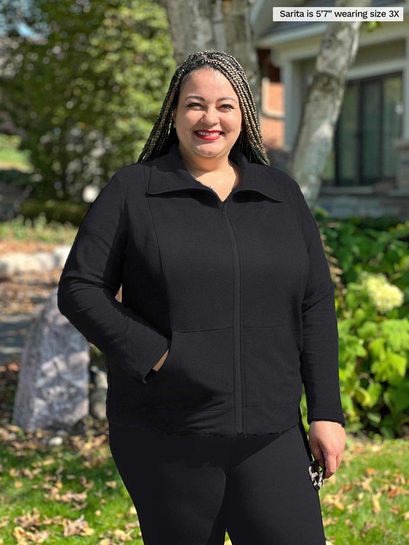 Miik model plus size Sarita (5'7", size 3x) smiling wearing an all black outfit: Miik's Shaelyn full zip luxe fleece jacket and high waisted legging 