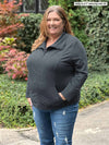 Miik model plus size Kelly (5'7", size 3x) smiling while standing sideway wearing Miik's Shaelyn full zip luxe fleece jacket in granite with jeans