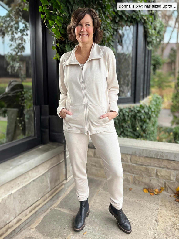 Miik founder Donna (5'6", small) smiling wearing a matching fleece set in oatmeal melange with boots. Donna is wearing Miik's Shaelyn full zip luxe fleece jacket along with the Linaya jogger