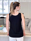 Woman standing with her back towards the camera showing the back of Miik's Shandra reversible tank top in black with white jeans
