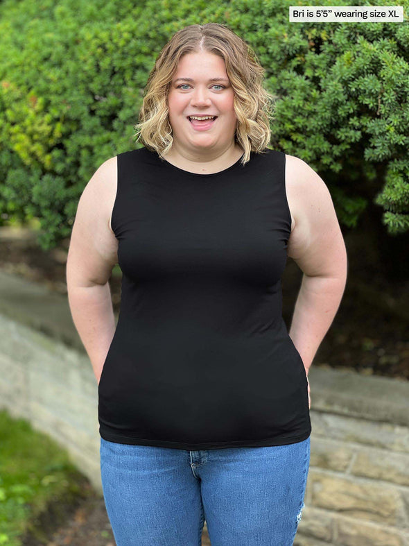 Miik model Bri (size XL, five foot five) wearing Shandra reversible tank top in black, reversed with the high neck in front.