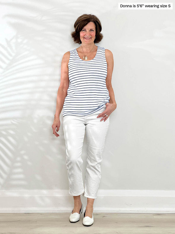 Miik founder Donna (5'6", small) smiling wearing Miik's Shandra reversible tank top - coastal stripe with a a white jeans