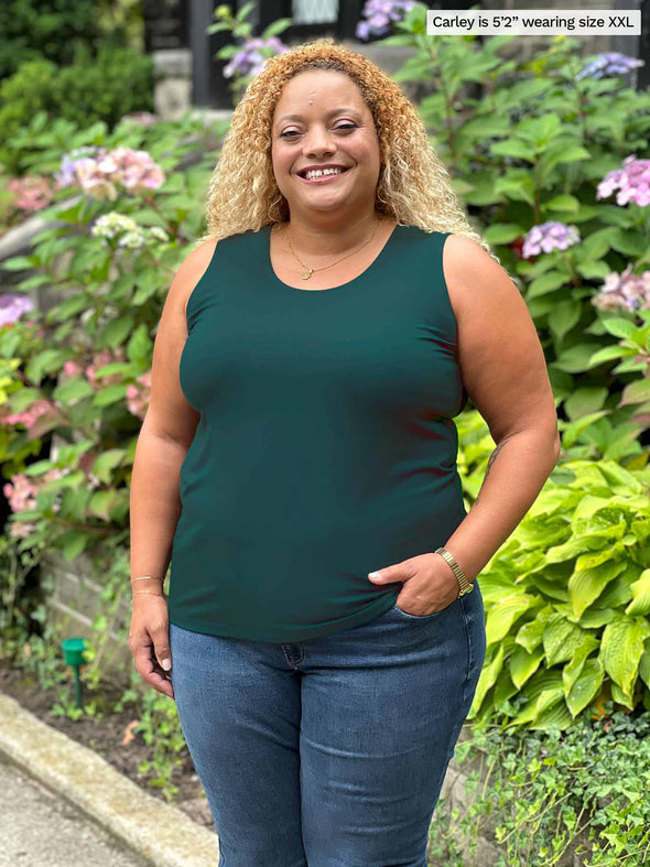 Miik model Carley (size XXL, five foot two) wearing Shandra reversible tank top in pine green, with the scoop neck in front.