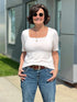 Woman wearing a white shirt and blue jeans standing outdoors. 