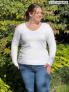 Woman standing in nature wearing Miik's Shannon long sleeve tee in white with jeans.