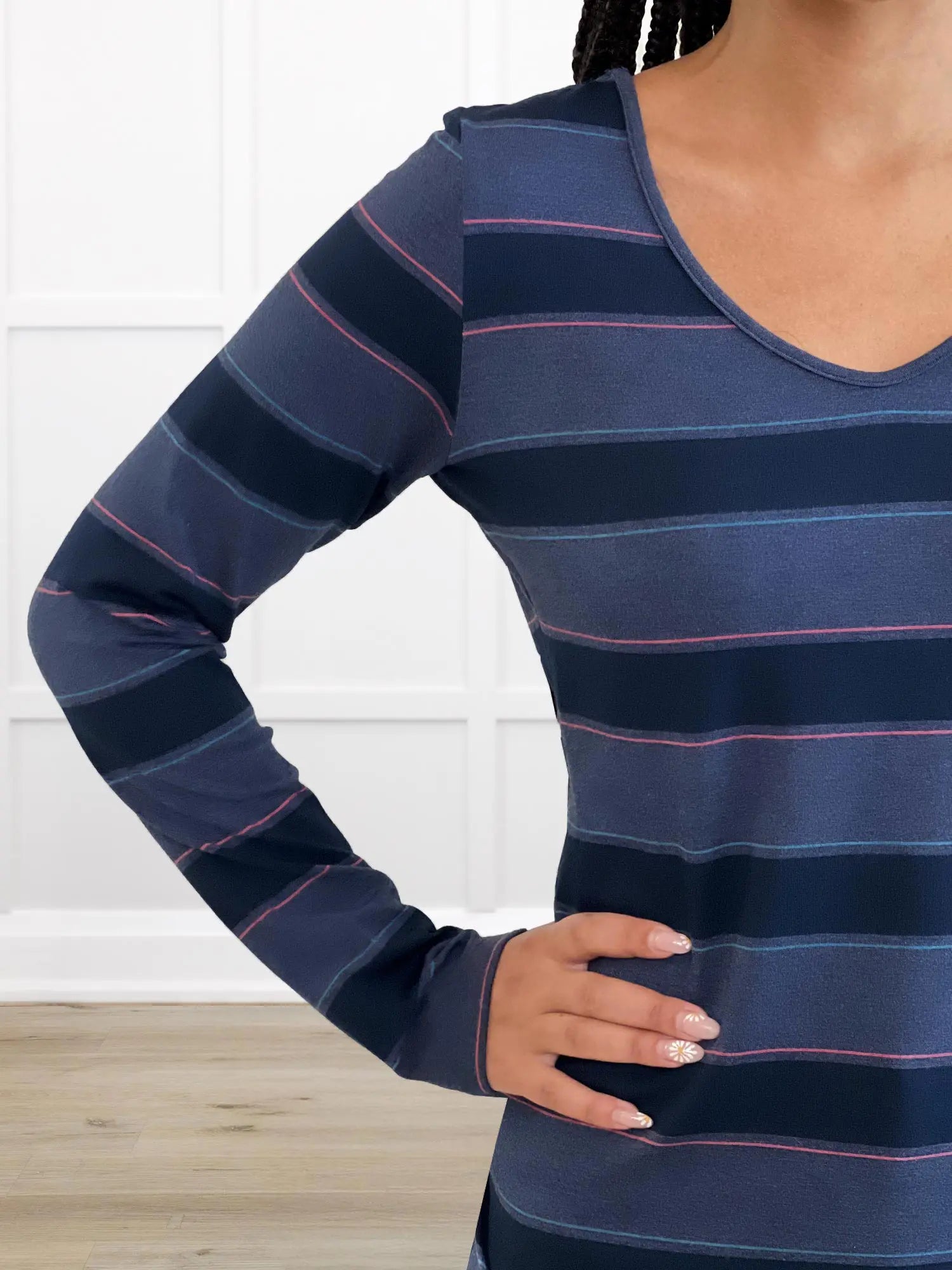 Navy blue and pink striped long-sleeve shirt worn by a person against a white background 
