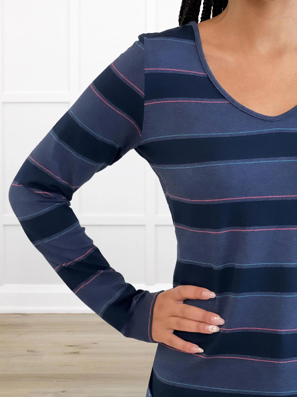Navy blue and pink striped long-sleeve shirt worn by a person against a white background 