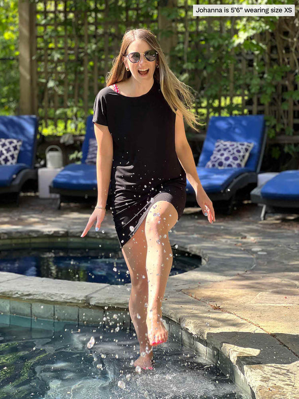 Miik model Jo (5'6", xsmall) having fun in the pool wearing Miik's Sia dolman-sleeve cocoon tunic in black as a cover up 