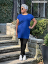 Miik model Keethai (5'5", medium) smiling and looking away wearing Miik's Sia dolman-sleeve cocoon tunic in ink blue and black legging