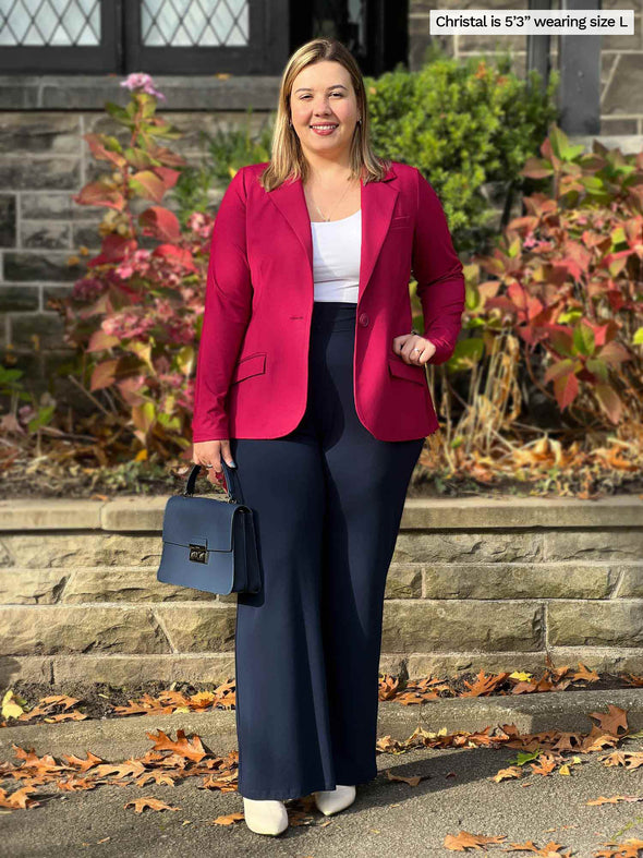 Miik model Christal (5'3", size large) wearing Miik's Sienna girlfriend blazer unbuttoned in bordeaux red over a white tank top and navy dress pants.