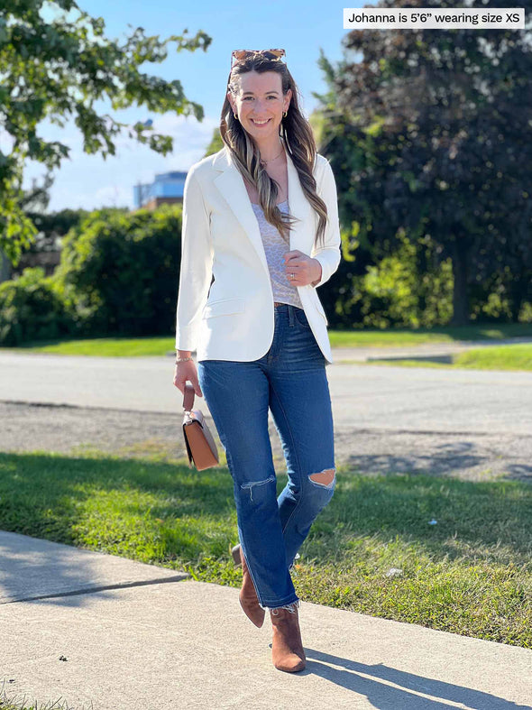 Woman walking outside wearing Miik's Sienna girlfriend blazer in off white with a tank and ripped jeans.