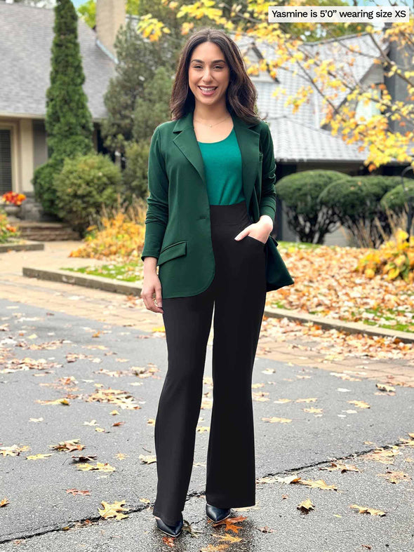 Miik model Yasmine (5'0", size xsmall) wearing Miik's Sienna girlfriend blazer in pine green over a jade green tank top and black dress pants.