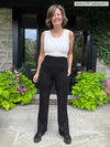 Miik founder Donna (five feet six, small) smiling and looking away wearing Miik's Sierra high waisted pocket pant in black with a white tank top