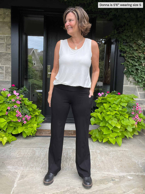Miik founder Donna (five feet six, small) smiling and looking away wearing Miik's Sierra high waisted pocket pant in black with a white tank top