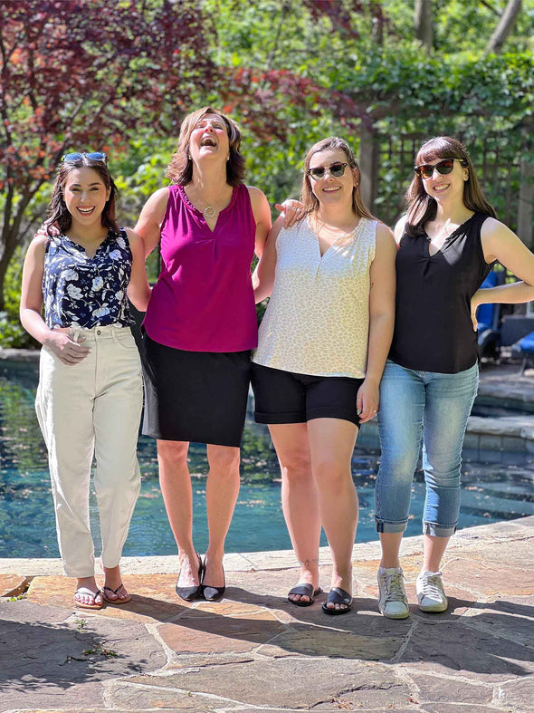 Miik models Yasmine, Sofia, Christal and founder Donna smiling while standing next to each other in front of a pool wearing the four different colours of Miik's Skye ruffle neck blouse: blossom, ruby, cobblestone and black 