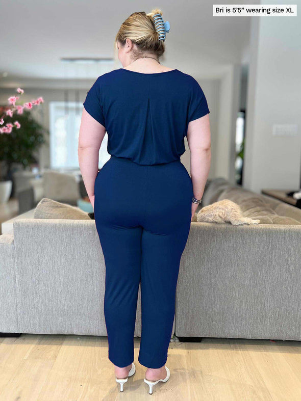 Miik model Bri (5’5”, xlarge) standing with her back towards the camera showing the back of Miik's Stef v-neck open-back capri jumpsuit
