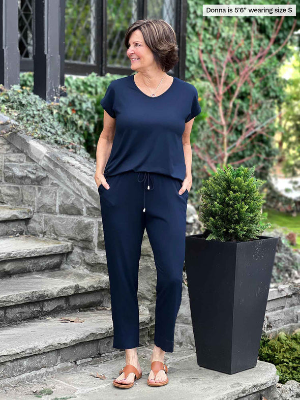 Miik founder Donna (5'6", small) smiling and looking away wearing Miik's Stef v-neck open-back capri jumpsuit in navy